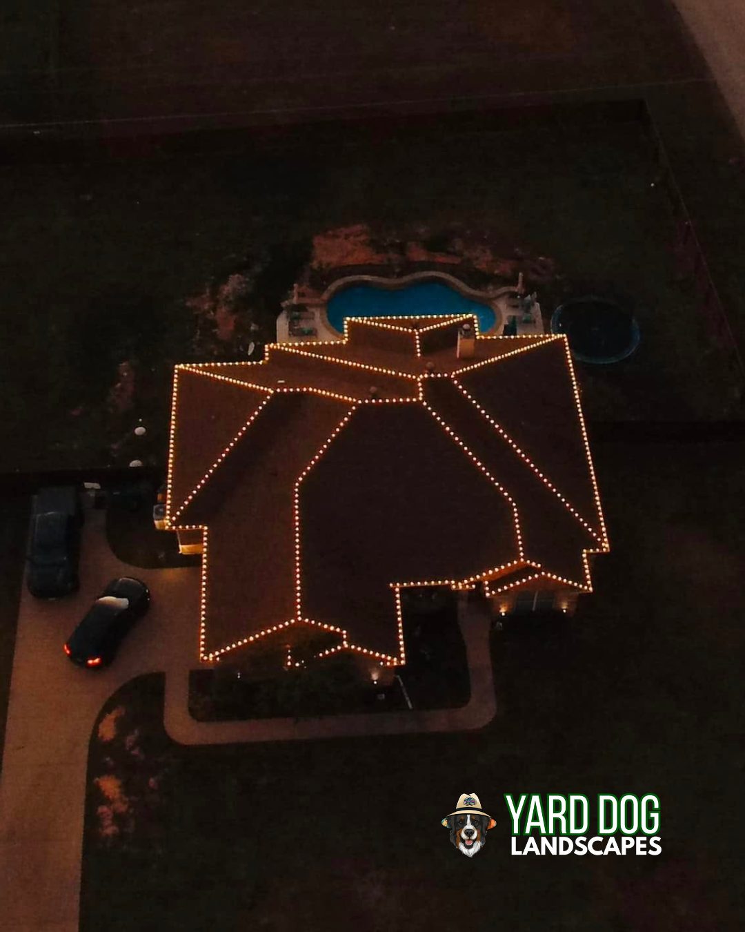 Drone view of a lit East Texas home at night with continuous Christmas light coverage