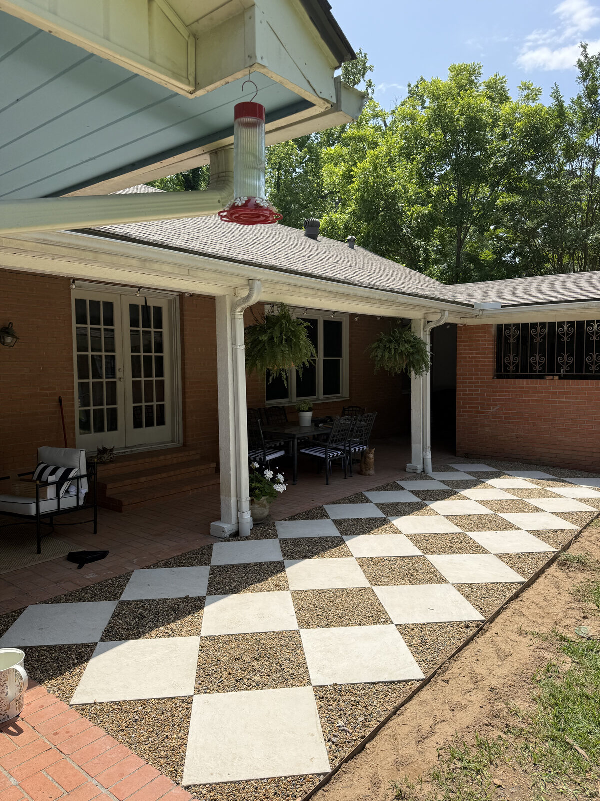 Finished checkerboard concrete paver patio with gravel joints off a covered porch in East Texas