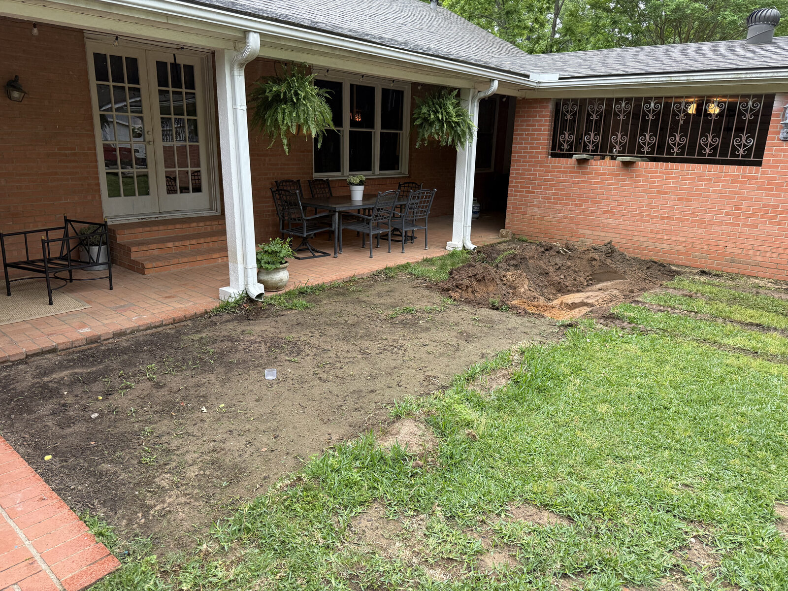 Patchy backyard before Yard Dog Landscapes built a checkerboard paver patio in East Texas