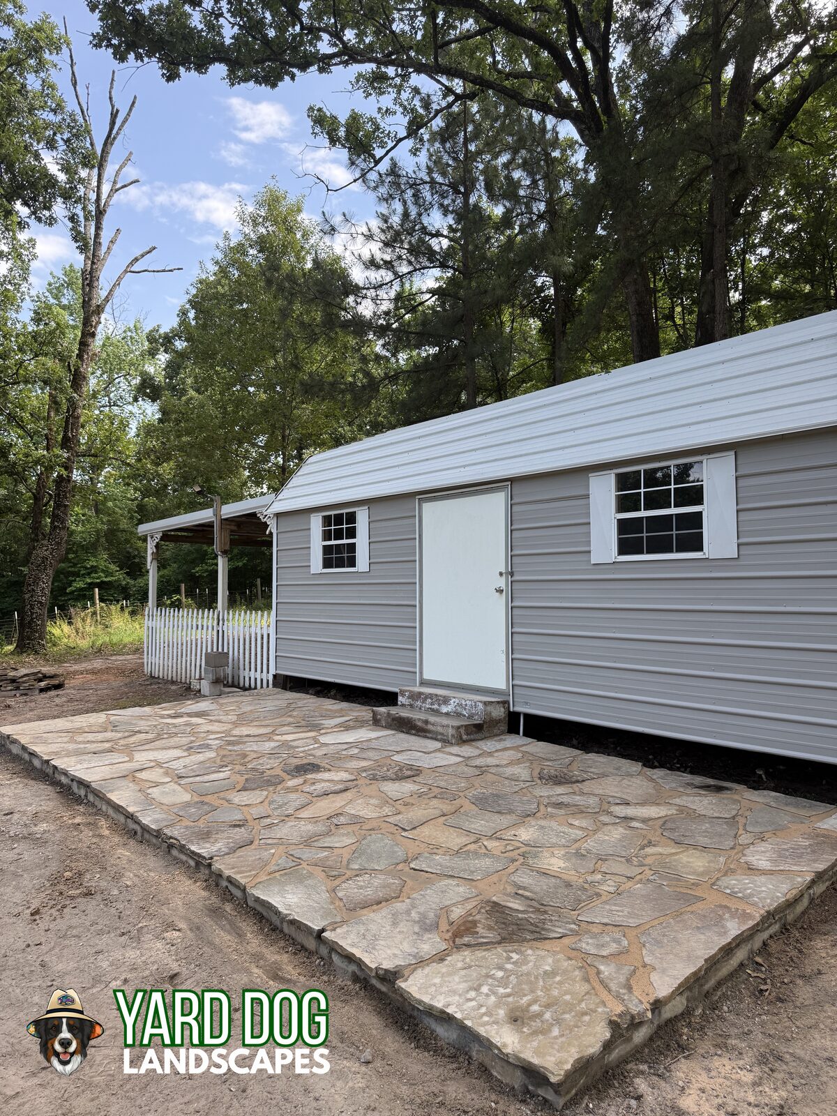 Finished flagstone patio with a stone border in front of a workshop in East Texas