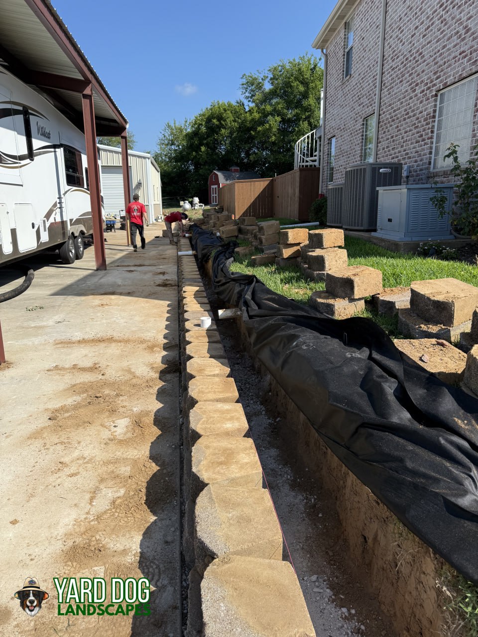 New base course set with drainage fabric and pipe behind a block retaining wall in East Texas