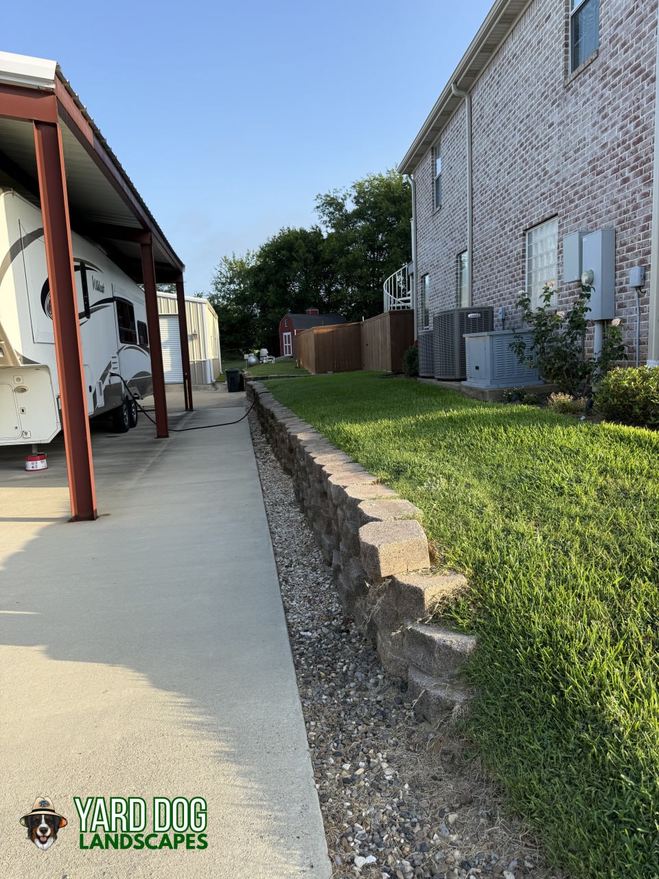 Old failing block retaining wall crumbling along a concrete driveway before Yard Dog Landscapes rebuilt it in East Texas