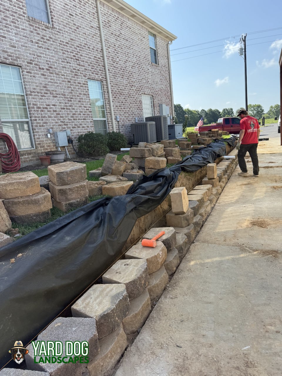 Yard Dog crew setting segmental block and drainage fabric on a retaining wall in East Texas