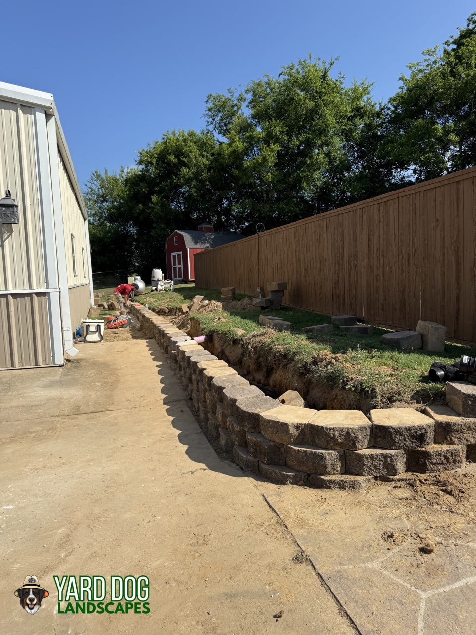 New segmental block retaining wall going up in courses along a driveway in East Texas