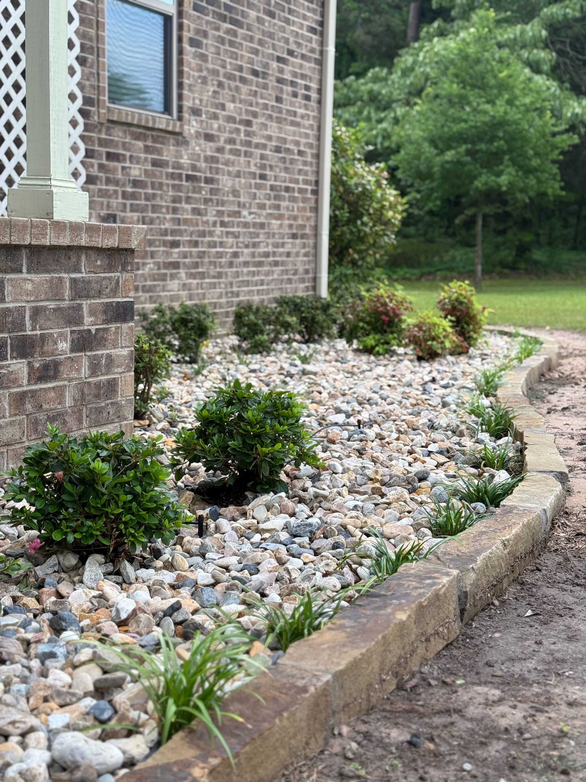 River rock drainage bed alongside a brick home