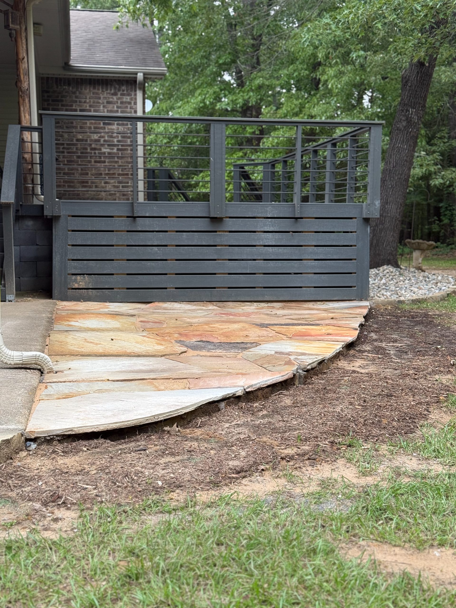 Backyard flagstone landing under a wood deck