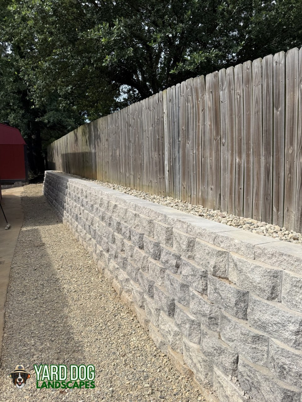 Completed block retaining wall with capstones and a gravel drainage strip in East Texas