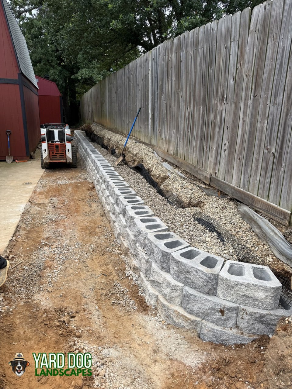 New segmental block retaining wall going up with gravel drainage behind it in East Texas