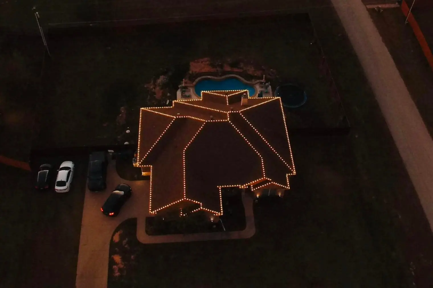 Aerial view at night of an East Texas home with warm white Christmas lights outlining the roofline