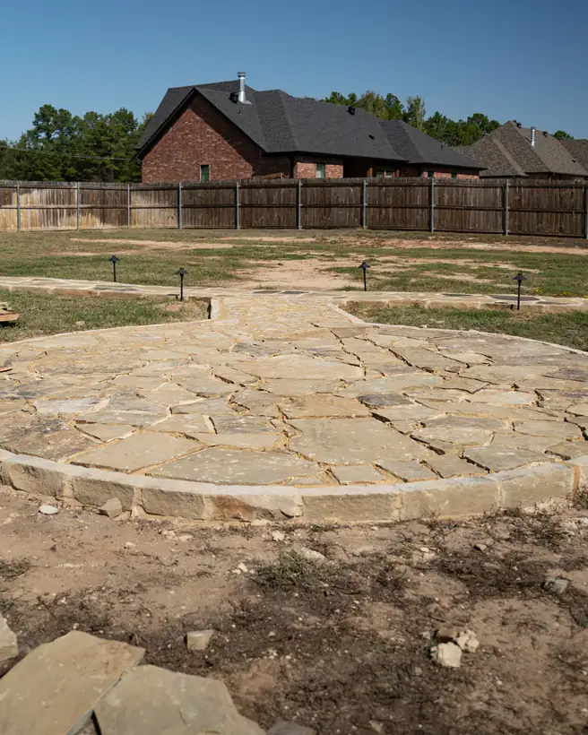 Round flagstone seating area with its chopped stone border, path lights behind, Kilgore, TX