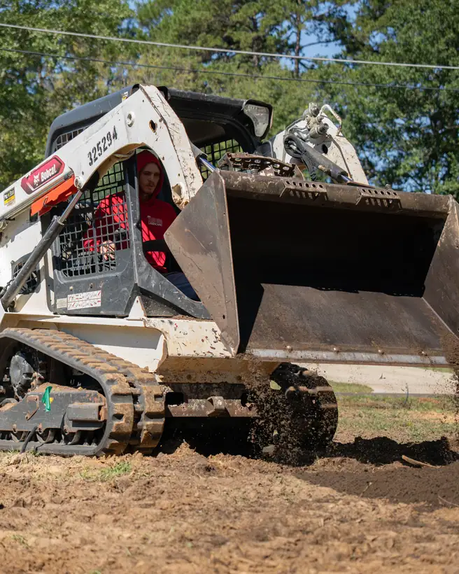 Track loader pushing topsoil out across the yard, Longview, TX